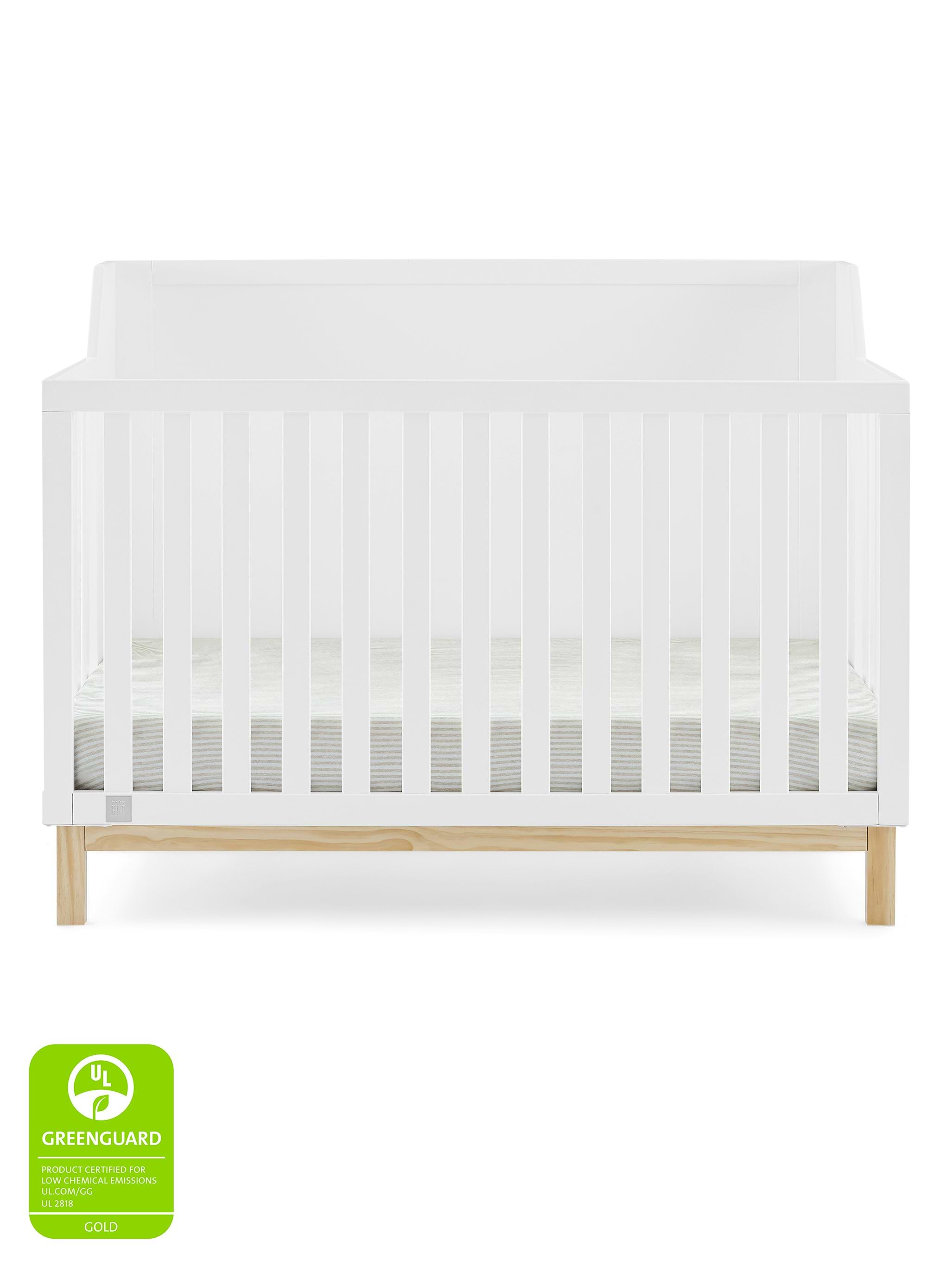 White wooden convertible crib with vertical slats and light wood frame.
