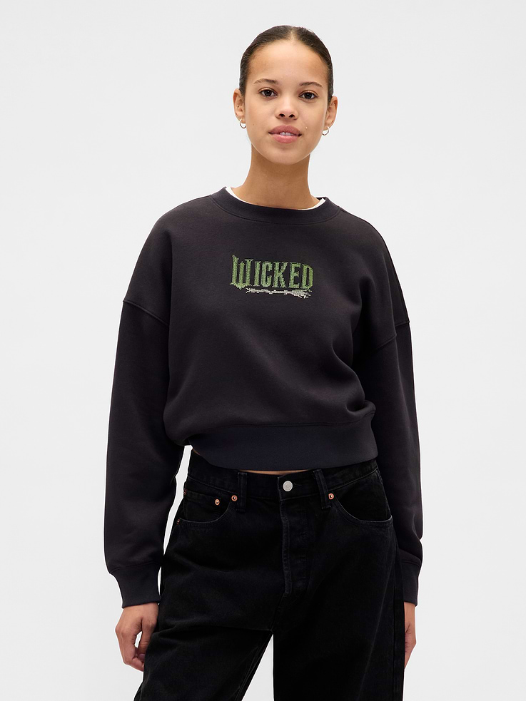 Image 1 of 2, A limited-edition capsule, inspired by the magic found in unexpected people & places. In celebration of the upcoming movie Wicked: For Good., Soft cotton-blend fleece oversized sweatshirt in a cropped length., Crewneck., Long sleeves with drop shoulders., Banded cuffs & hem., Wicked graphic at front., Made with 23% recycled polyester. Compared to virgin materials, using recycled materials helps reduce resource use and waste., Explore our GapSweats Guide ., Product #844942