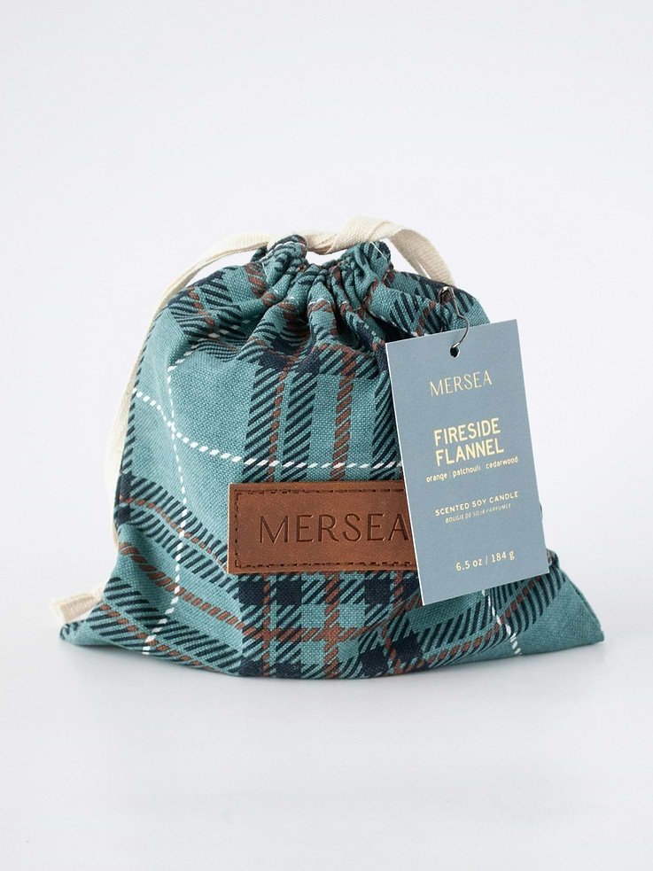 Image 1 of 2, Orange, Patchouli, Cedarwood., Zesty orange is grounded by earthy patchouli and freshly chopped cedarwood for a scent that is cozy and comforting, like a crackling fire and soft flannel on cool autumn nights., The ever-popular Sandbag Candle, now dressed in a charming plaid bag., Our classic 6.5-ounce candles are hand-poured into sheer white glass vessels that can be beautifully repurposed long after the flame fades., Thoughtfully packaged with matches in a reusable plaid bag—perfect for stashing keepsakes or seasonal treasures—this candle is finished with our signature uplifting gift tag, making it a perfect gift for any occasion.