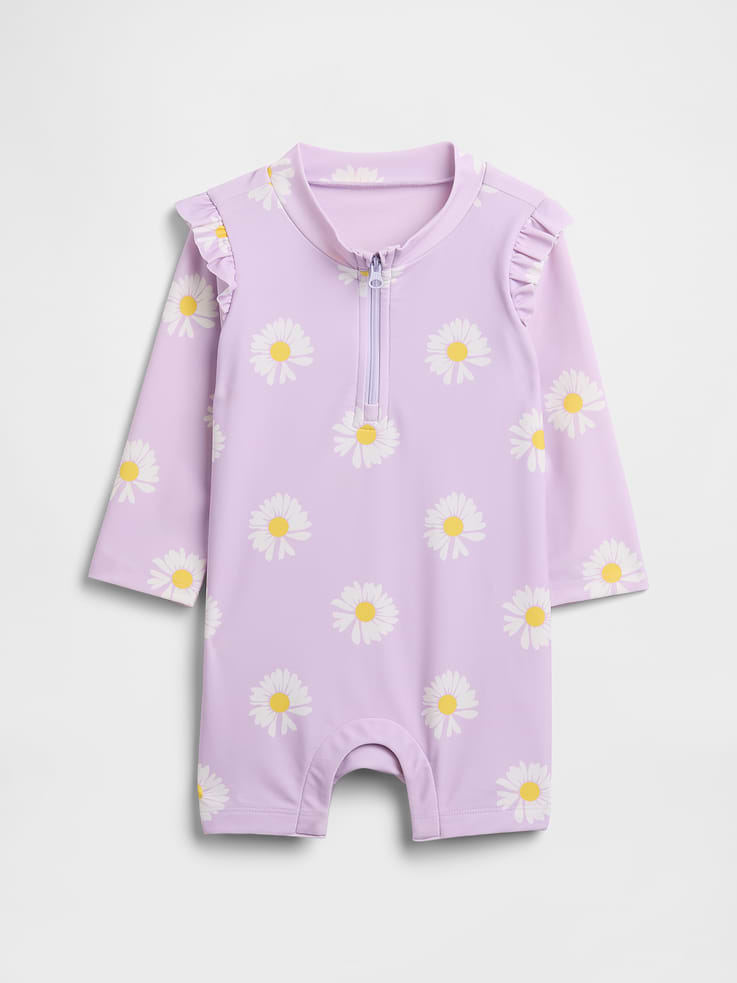 Image 1 of 3, Stretch knit., Ruffle trim at shoulders, long sleeves., Round neckline, quarter-zip front., Hidden snaps at inseam for easy dressing and diapering., Select styles have allover print., UPF 50+: Excellent UV Protection., Accords with ASTM Standard D6603., This product was made in a factory that invests in gender equity and women’s empowerment through RISE. Learn more at gapinc.com/equity., Product #1172724