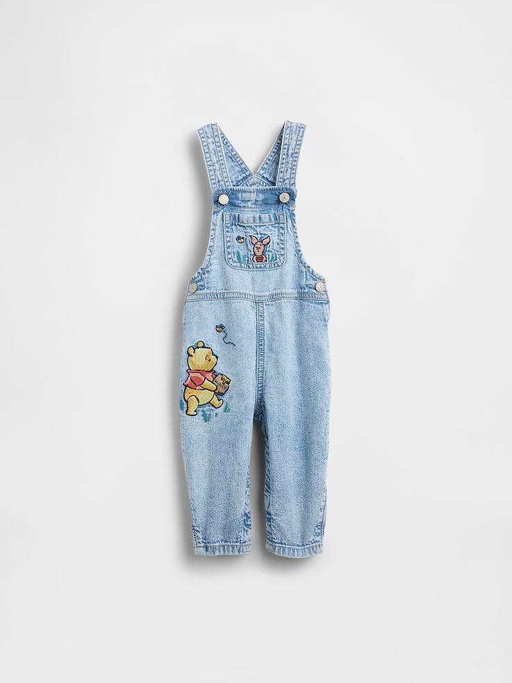 Image 1 of 5, A capsule capturing the magic of the Hundred Acre Wood. Created from heirloom fabrics and made with playful details. Celebrating growing up, together., Soft cotton denim baby overalls., Square neck., Adjustable tank straps, racerback., Front bib pocket., Button closure at sides., Back patch pockets., Assorted Winnie the Pooh graphics at front., Snaps at inseam for easy dressing and diapering., This pair of overalls is part of our water-saving Washwell program. Compared with conventional wash methods, Washwell uses at least 20% less water., This product was made in a factory that invests in gender equity and women’s empowerment through RISE. Learn more at gapinc.com/equity ., Explore our babyGap Guide ., Product #883667