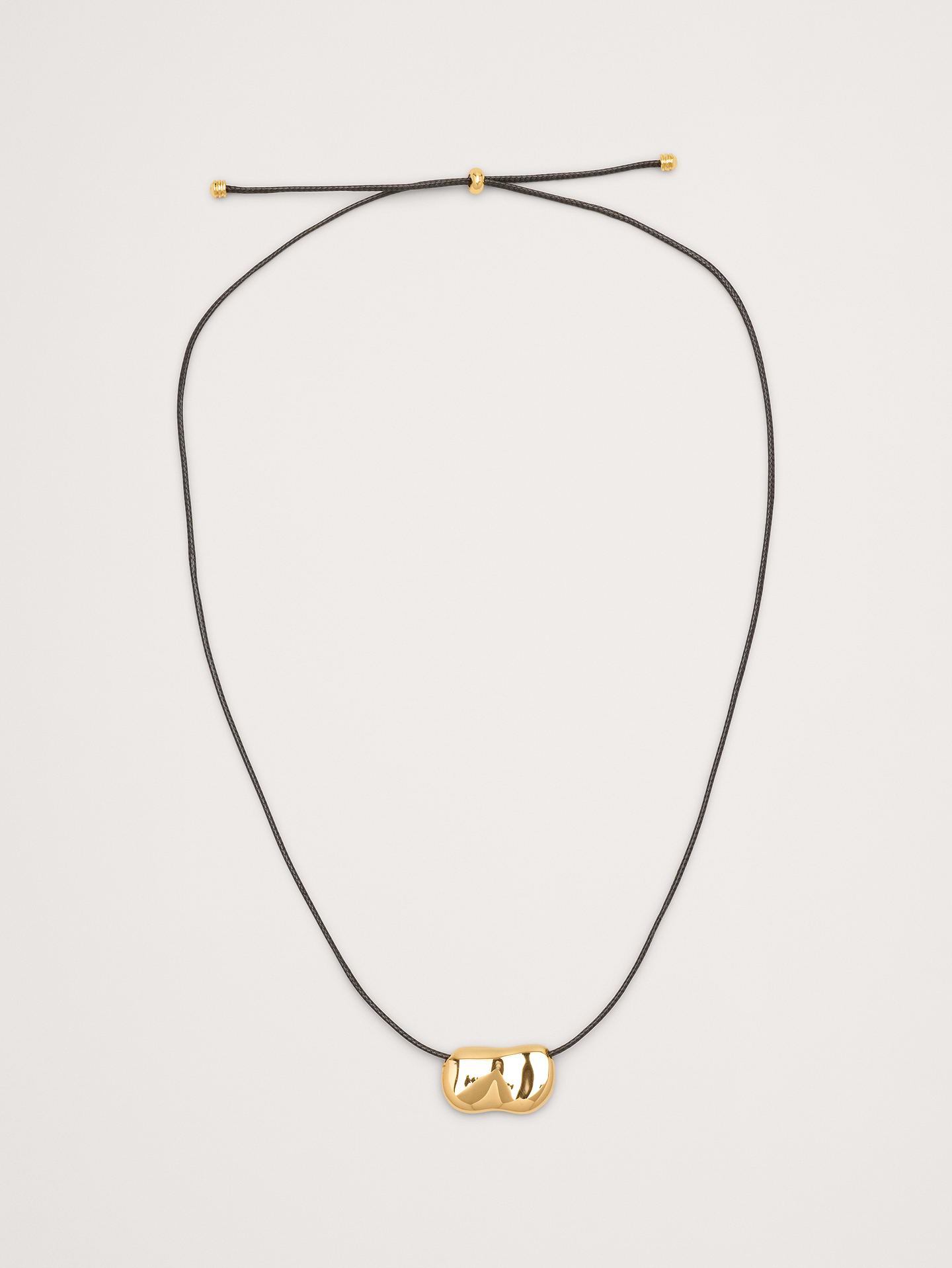 Image 1 of 3, The Pebble Necklace is a minimalist statement: a sleek pebble-shaped pendant in your choice of gold-plated or silver finish on a black leather cord, adding a subtle yet striking accent to any outfit., Heaven Mayhem: Los Angeles–based accessories brand creating vintage‑inspired statement pieces reimagined for the modern wardrobe—timeless, sculptural designs made to elevate everyday style., 18k-gold or silver-plated stainless steel., Slider closure., Product #899764