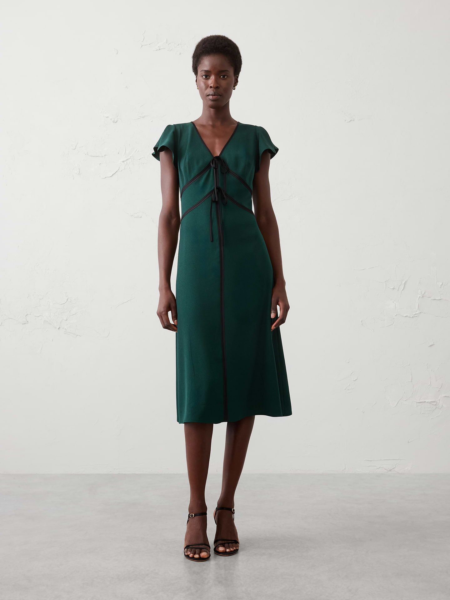 Image 1 of 3, V-neckline. Cap flutter sleeves., Satin trim frames the neckline and bodice., Double tie‑front accents., Fitted at the waist., Hidden side zipper closure., Gently flared skirt., Made exclusively for Banana Republic Factory., Product #1178232