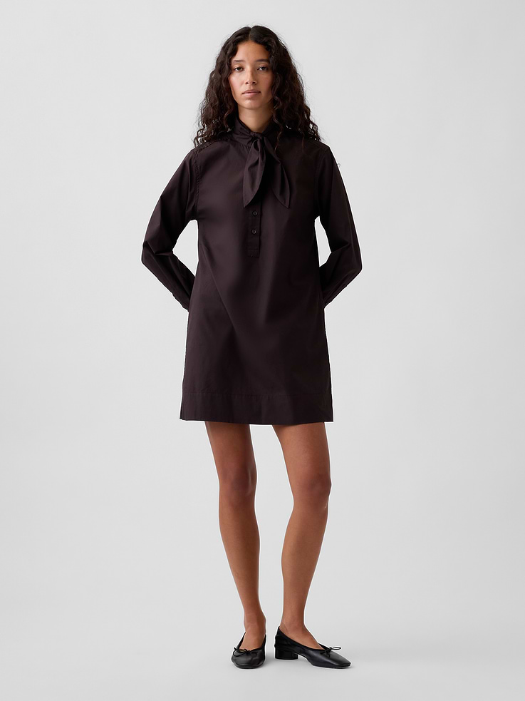 Image 1 of 5, Smooth cotton poplin mini shift dress., Tie neck with front button placket., Long sleeves with button cuffs., Back yoke seam., Made with 100% organically grown cotton which is grown without the use of synthetic pesticides and fertilizers., This product was made in a factory that invests in gender equity and women’s empowerment through RISE. Learn more at gapinc.com/equity ., Product #1184719