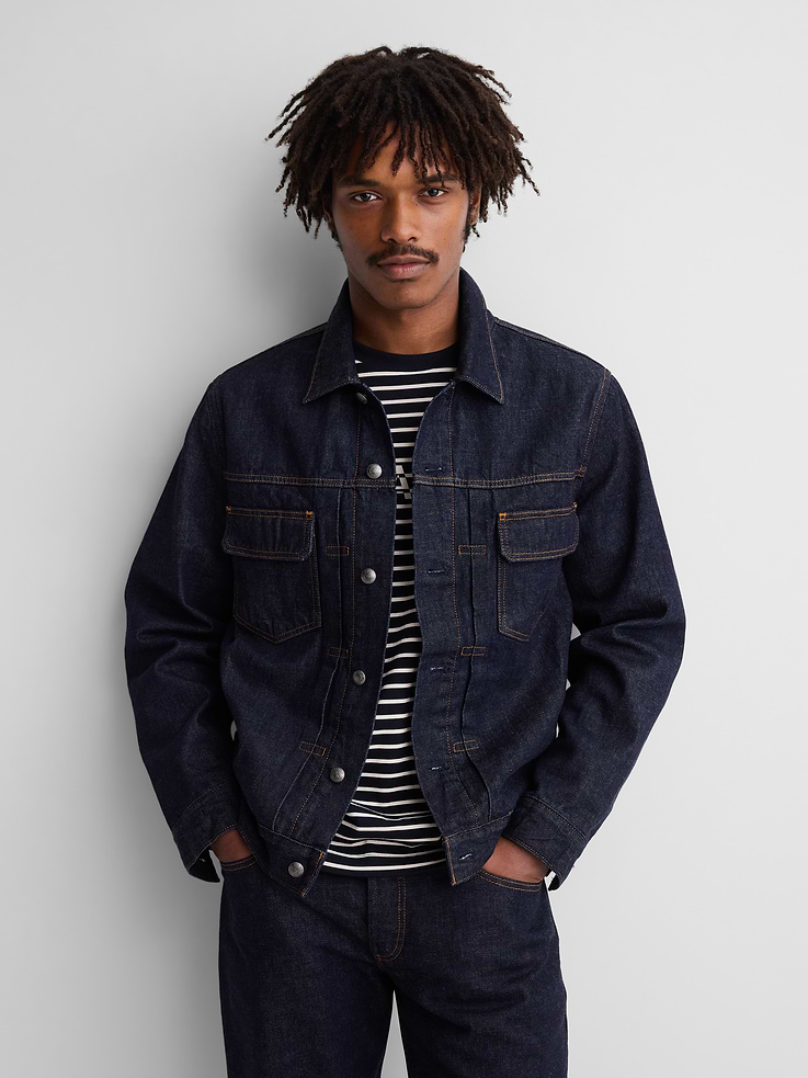 Image 1 of 10, Authentic, rigid Japanese denim jacket. In a classic fit., Spread collar., Long sleeves with logo button cuffs., Logo button-front and rivet hardware detailing., Patch pockets at chest., Seamed detailing at front., On-seam side pockets., Button-tabs and logo leather patch at rear hem., Soft twill lining with Gap x A.P.C. prints., Responsibly Made: This product is part of our water-saving Washwell program. Compared with conventional wash methods, Washwell uses at least 20% less water., Product #1179804