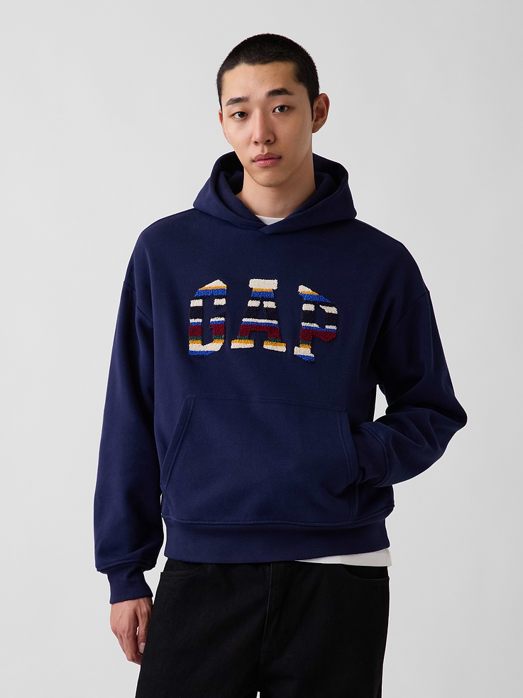 Image 1 of 5, Soft cotton-blend fleece pullover hoodie. In an oversized fit., Hooded neckline., Long sleeves with drop shoulders., Gap logo with Happy Stripe design at front., Kanga pocket., Banded rib cuffs and hem., Made with 52% Protocol cotton verified by the U.S. Cotton Trust Protocol, a program which works with farms committed to improving their environmental footprint by minimizing water usage and improving soil health (Claim No. 10127)., Made with 23% recycled polyester. Compared to virgin materials, using recycled materials helps reduce resource use and waste., This product was made in a factory that invests in gender equity and women’s empowerment through RISE. Learn more at gapinc.com/equity ., Product #1189393