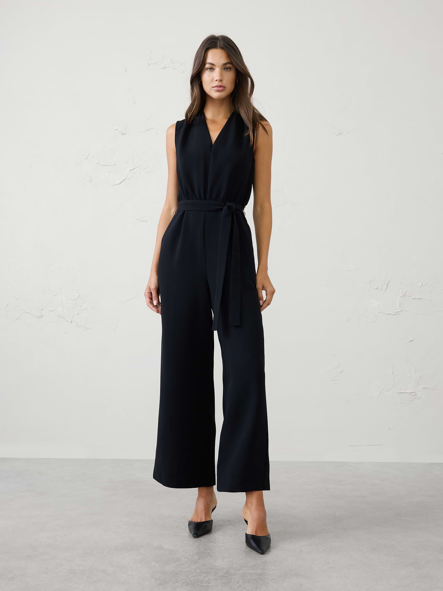 Image 1 of 3, Crafted from our soft suiting crepe, this jumpsuit combines a refined V‑neckline with a defined, belted waist for a flattering silhouette. Polished and effortlessly versatile, it’s a timeless one‑and‑done piece that transitions seamlessly from work to special occasions., V-neckline. Sleeveless., Soft pleating at the neckline., Defined waist seam., Self‑tie belt., Off-seam side pockets., Relaxed fit through the hips., Back keyhole opening with button closure., Soft gathering at the back waist adds shape and comfort., Made exclusively for Banana Republic Factory., Product #1185689