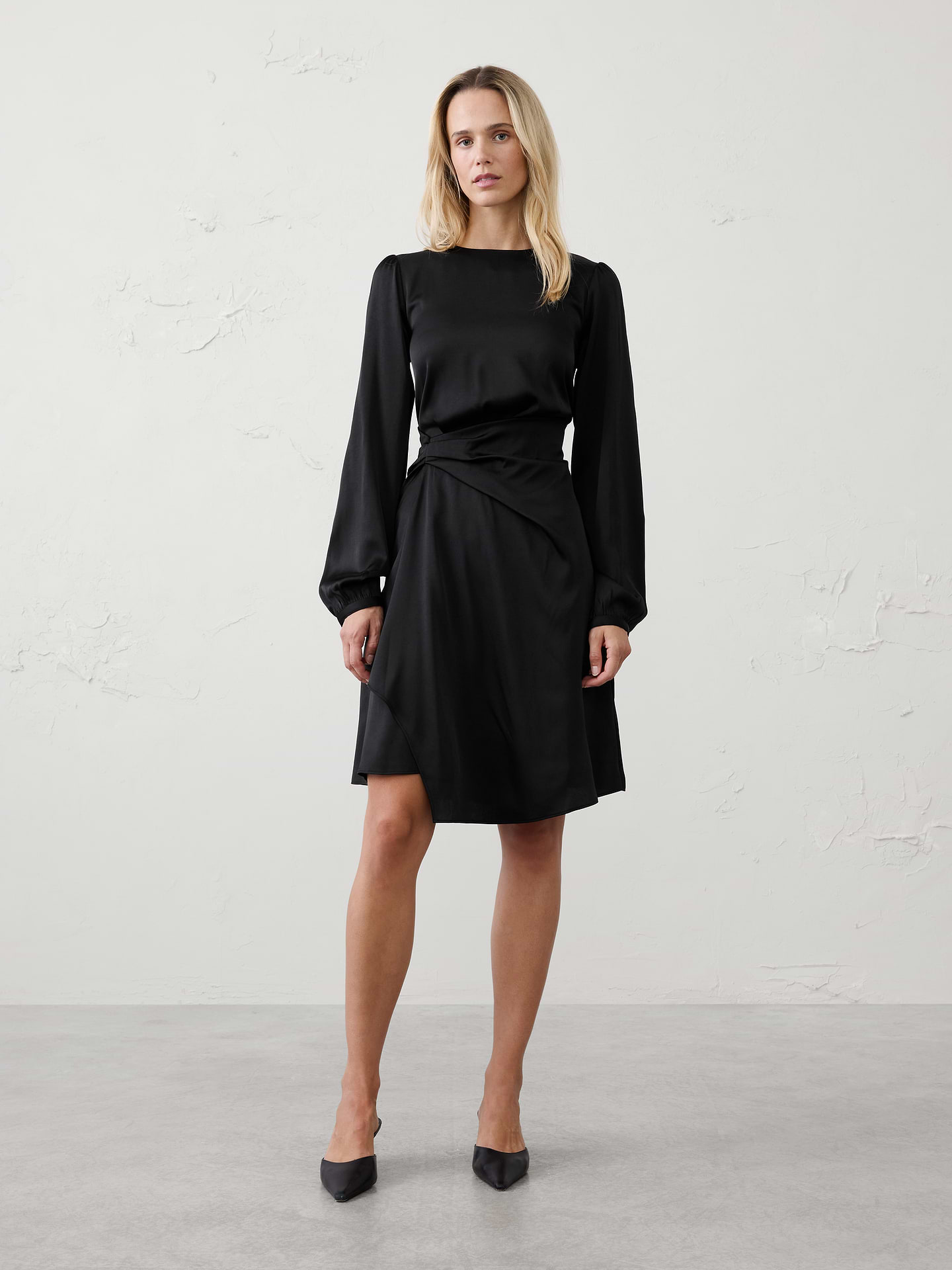 Image 1 of 4, Elegant asymmetric draping defines the waist while creating an effortlessly polished look for any occasion., Round neckline. Long sleeves with buttoned cuffs., Wrap-inspired skirt with cascading detail., Hidden back zipper closure., Back waist seam with back darts., Asymmetrical hem., Made exclusively for Banana Republic Factory., Product #1185674