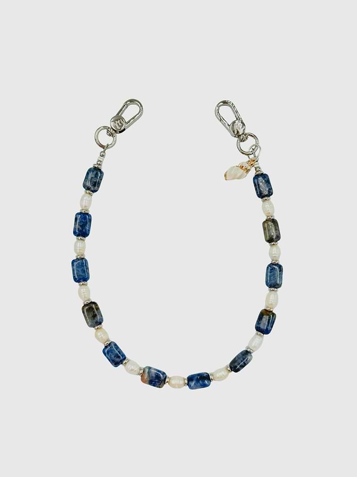 Image 1 of 1, Cool ocean tones meet natural elegance in the Bay Strap, handcrafted with flat stone agate beads, freshwater pearls, and silver spacer accents finished with a natural shell charm for a subtle coastal detail., Universal Phone Hitch required to attach to your phone case, sold separately., Over time, certain bead colors may lose their vibrancy due to exposure to air, water, and heat., Due to natural variations in gemstones and beads, product may differ slightly from displayed photos., The CAEP in no way guarantees the integrity of your smartphone when using this strap.