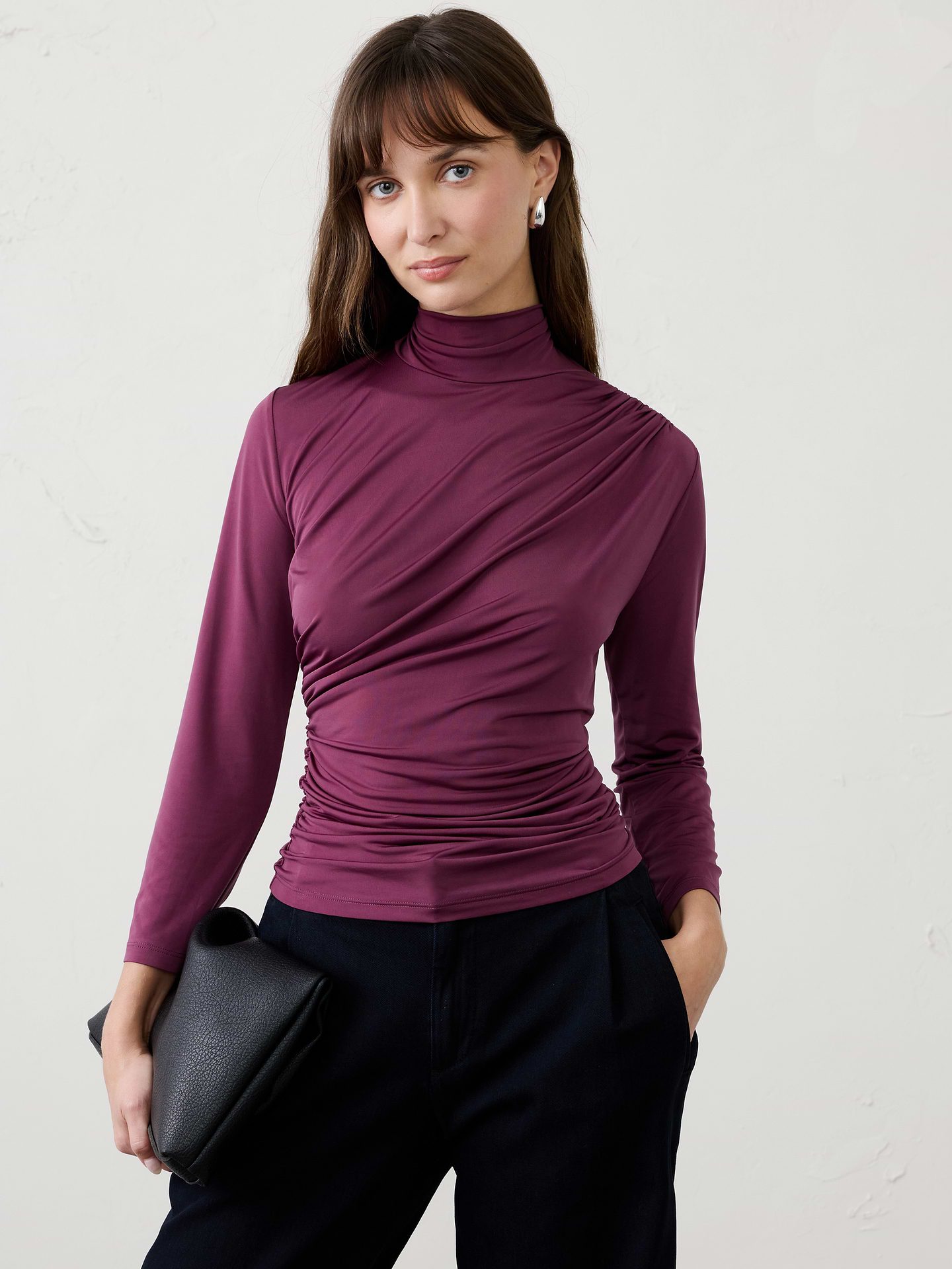 Image 1 of 4, Made from a sleek jersey fabric with a silk‑like hand feel and matte finish, this top offers exceptional stretch and beautiful drape. The softly draped turtleneck creates an elevated silhouette, making it the perfect dressy top that remains comfortable enough for all‑day wear., Soft draped turtleneck. Three-quarter long sleeves., Diagonal ruching across the front., Gathered side seams enhance shape and contour the waist., Back features subtle shirring at the waist., Made exclusively for Banana Republic Factory., Product #1186021