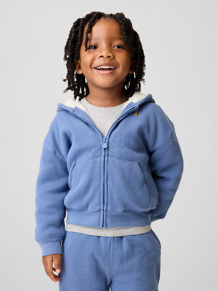 Image 1 of 4, Soft waffle-knit cotton full-zip hoodie with a cozy sherpa lining., Hooded neckline., Long sleeves with drop shoulders., Zipper front., Embroidered Brannan Bear at chest., Kanga pockets., Banded cuffs and hem., Sherpa lining made with 100% recycled polyester. Compared to virgin materials, using recycled materials helps reduce resource use and waste., This product was made in a factory that invests in gender equity and women’s empowerment through RISE. Learn more at gapinc.com/equity ., Product #1184879