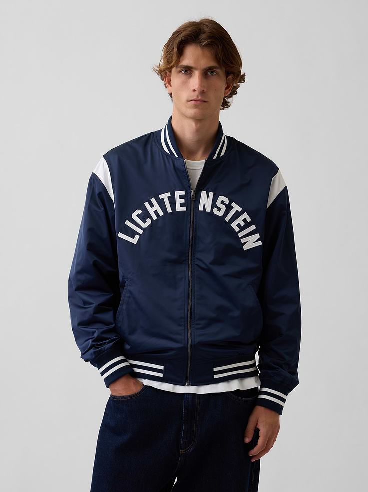 Image 1 of 10, Soft satin varsity jacket. In a relaxed fit., Mockneck., Long sleeves., Zipper front., Slant pockets., Roy Litchenstein's Standing Explosion inspired detailing at back., Litchenstein embroidered arch logo at front., Banded neck, cuffs, and hem with varsity stripe detailing., Product #1189392