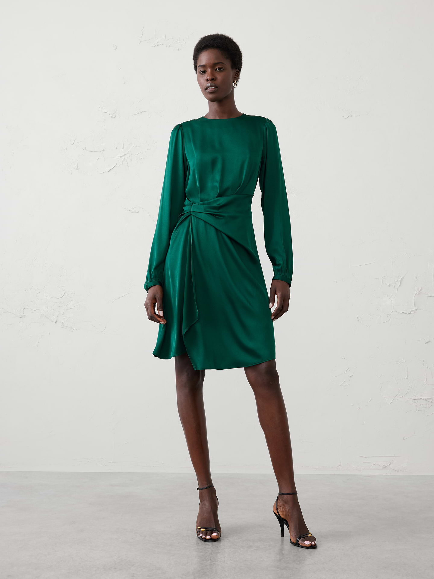 Image 1 of 4, Elegant asymmetric draping defines the waist while creating an effortlessly polished look for any occasion., Round neckline. Long sleeves with buttoned cuffs., Wrap-inspired skirt with cascading detail., Hidden back zipper closure., Back waist seam with back darts., Asymmetrical hem., Made exclusively for Banana Republic Factory., Product #1185674
