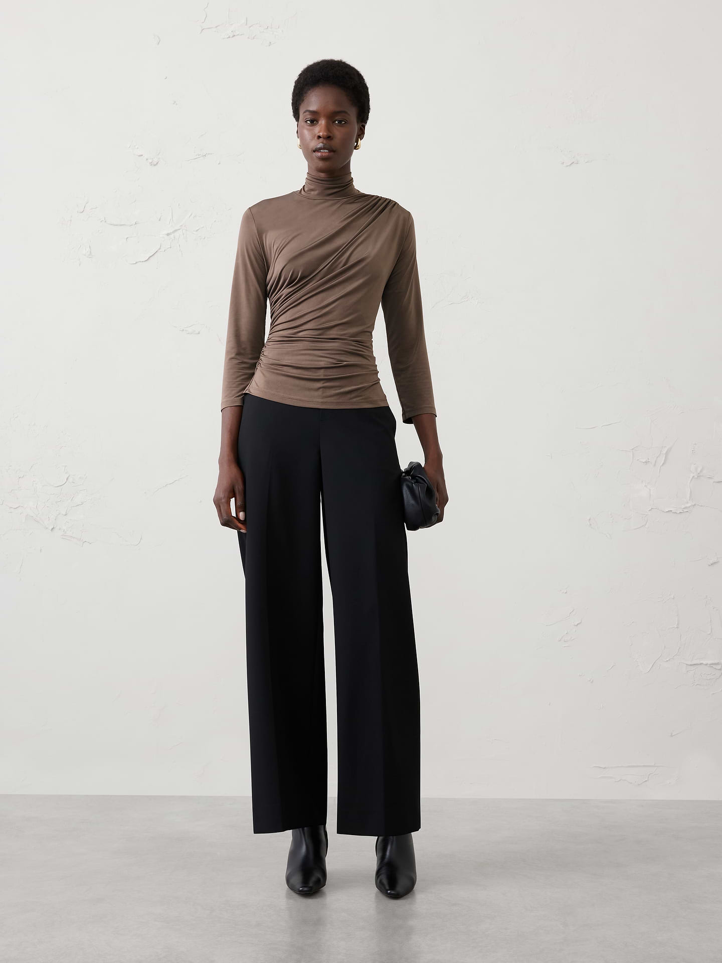 Image 1 of 4, Made from a sleek jersey fabric with a silk‑like hand feel and matte finish, this top offers exceptional stretch and beautiful drape. The softly draped turtleneck creates an elevated silhouette, making it the perfect dressy top that remains comfortable enough for all‑day wear., Soft draped turtleneck. Three-quarter long sleeves., Diagonal ruching across the front., Gathered side seams enhance shape and contour the waist., Back features subtle shirring at the waist., Made exclusively for Banana Republic Factory., Product #1186021