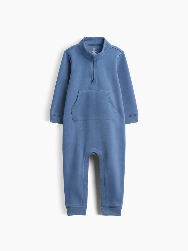 Image 1 of 3, Our softer than soft sweats. Brushed on the inside. Smooth on the outside. Made so that no two are alike., Soft cotton-blend fleece baby one-piece., Mockneck with quarter-zip closure., Long sleeves., Kanga pocket., Brannan Bear graphic at back., Banded cuffs., Snaps at inseam for easy dressing and diapering., Made with 52% Protocol cotton verified by the U.S. Cotton Trust Protocol, a program which works with farms committed to improving their environmental footprint by minimizing water usage and improving soil health (Claim No. 10127)., Made with 23% recycled polyester. Compared to virgin materials, using recycled materials helps reduce resource use and waste., This product was made in a factory that invests in gender equity and women’s empowerment through RISE. Learn more at gapinc.com/equity ., Product #1185473