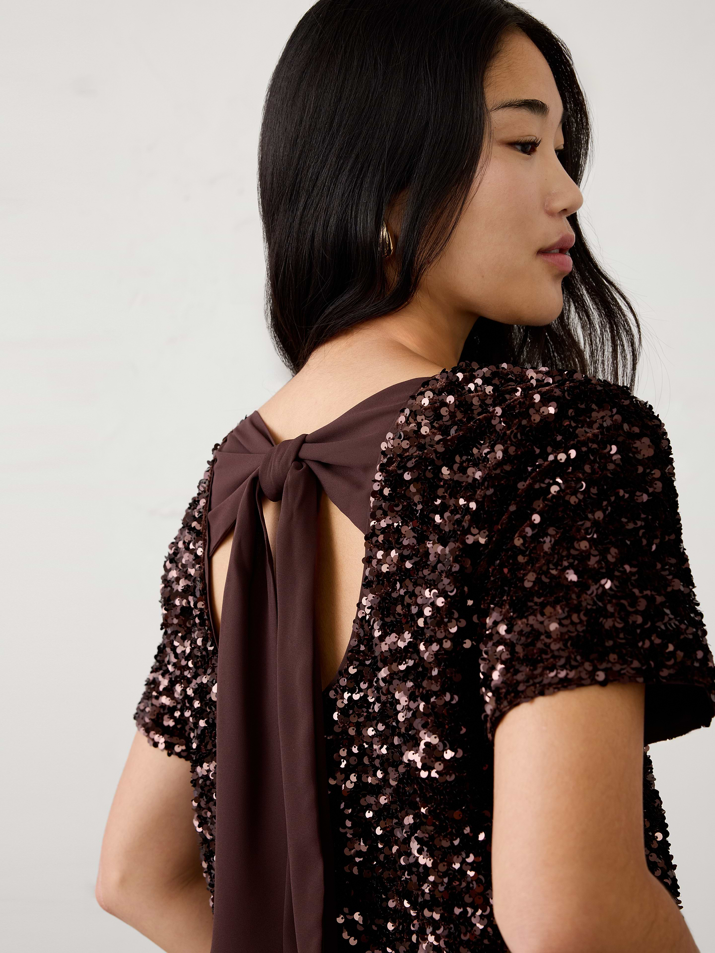 Image 1 of 4, Add effortless sparkle to your holiday wardrobe with this sequin top. Designed with a bow-back detail and open-back accent create an unexpected feminine finish., Crew neck. Short sleeves., Statement bow-back detail with an open back., Made exclusively for Banana Republic Factory., Product #1185894