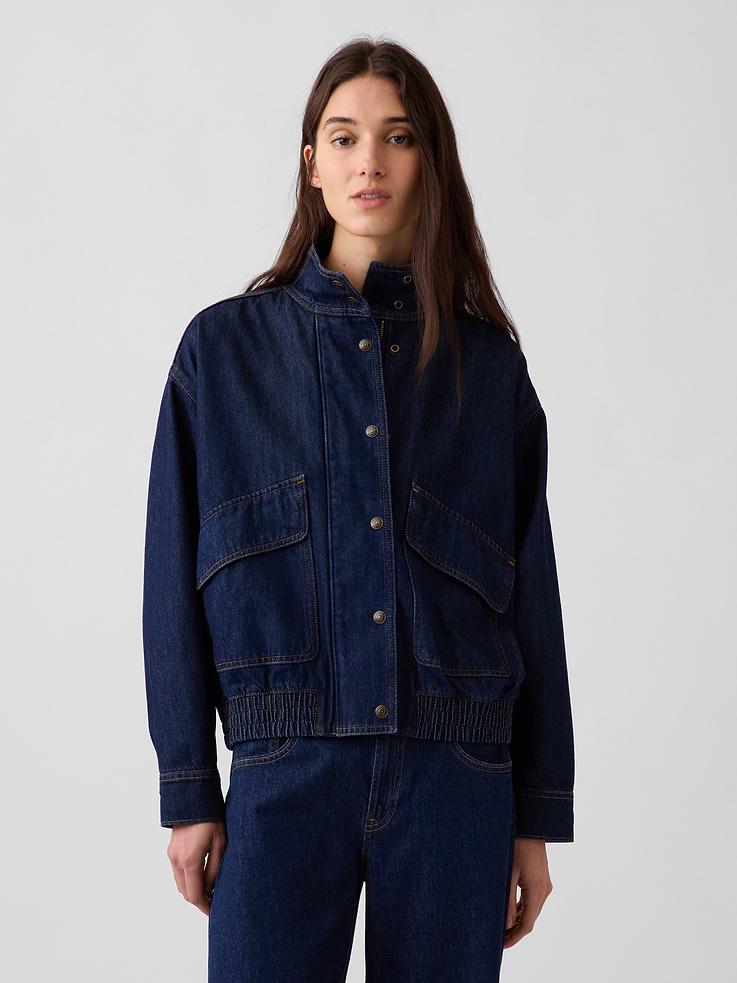 Image 1 of 6, Authentic, non-stretch denim bomber jacket. In an oversized fit., Mockneck., Long sleeves with drop shoulders and snap button cuffs., Concealed zipper front beneath full snap button placket., Vertical back seam., Front flap patch pockets., Elasticized hem., Responsibly Made: This denim jacket is part of our water-saving Washwell program. Compared with conventional wash methods, Washwell uses at least 20% less water., More Sustainable Cotton: Made with 5% recycled cotton. Compared to virgin materials, using recycled materials helps reduce resource use and waste., This product was made in a factory that invests in gender equity and women’s empowerment through RISE. Learn more at gapinc.com/equity ., Product #1186418