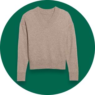 Beige V-neck knit sweater with long sleeves and ribbed cuffs and hem on a green background.