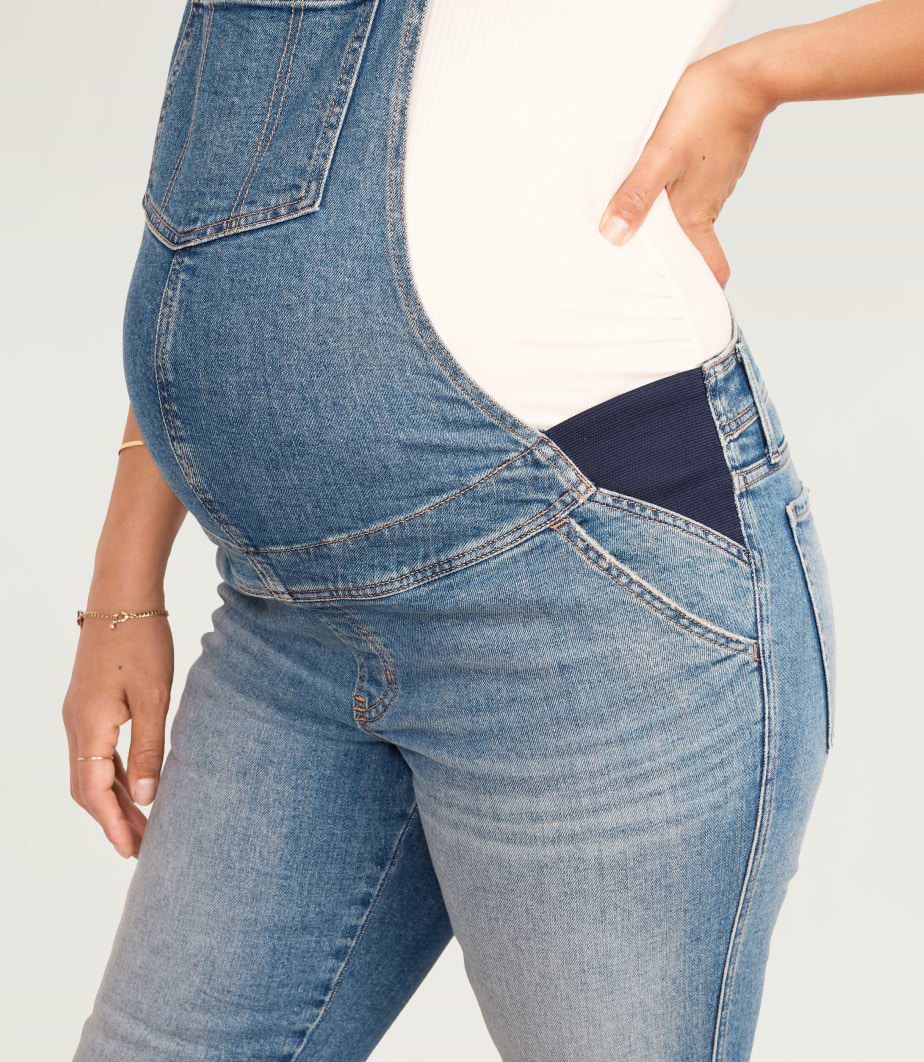 A pregnant model wearing maternity side-panel OG straight jean overalls.
