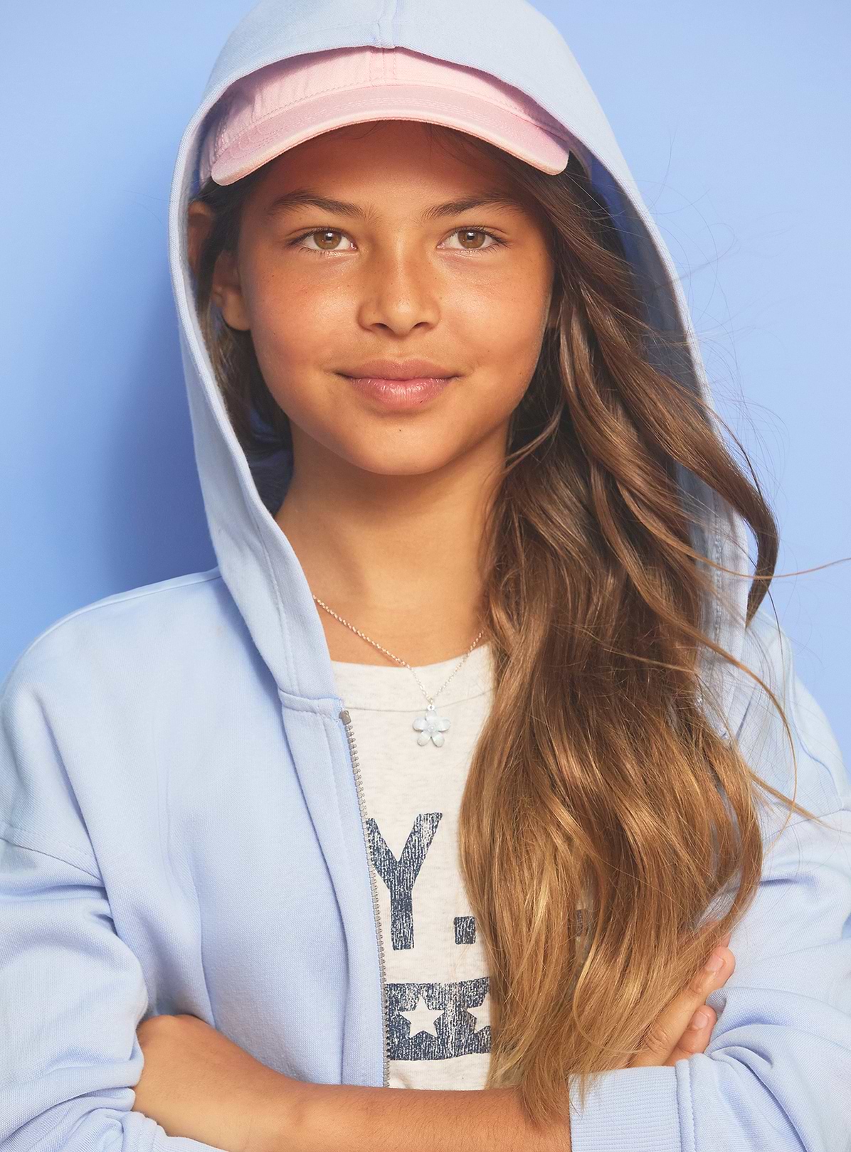 Image of a girl model wearing an Old Navy graphic tee, fleece hoodie and baseball cap.