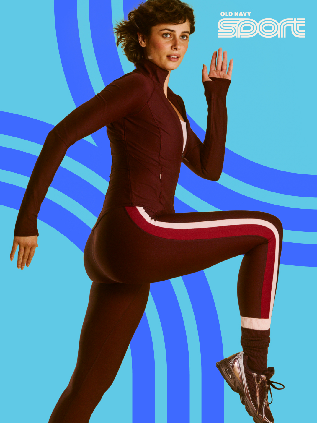 Person in a maroon athletic set with white and red side stripes lifts a knee in a running pose against a blue graphic background; “Old Navy Sport” text appears in the top right.