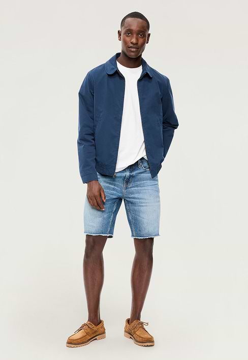 A male model wears a pair of slim fit jean shorts.