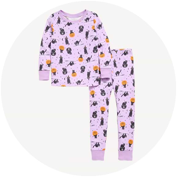 Lilac kids’ pajama set with long-sleeve top and pants, printed with black cats and orange jack-o’-lanterns.