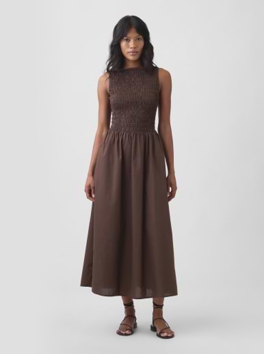 Model wearing a sleeveless brown dress with a smocked bodice and A-line midi skirt.