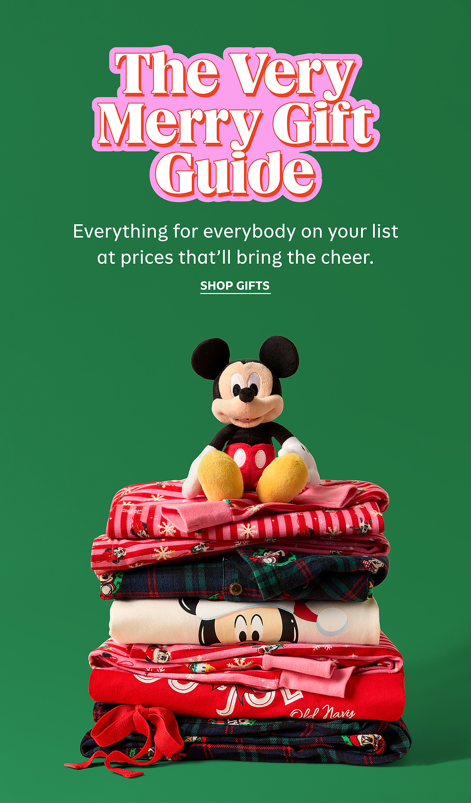 Green holiday ad: “The Very Merry Gift Guide” text above a Mickey Mouse plush sitting on a stack of red and plaid holiday pajamas with “Shop Gifts” below.
