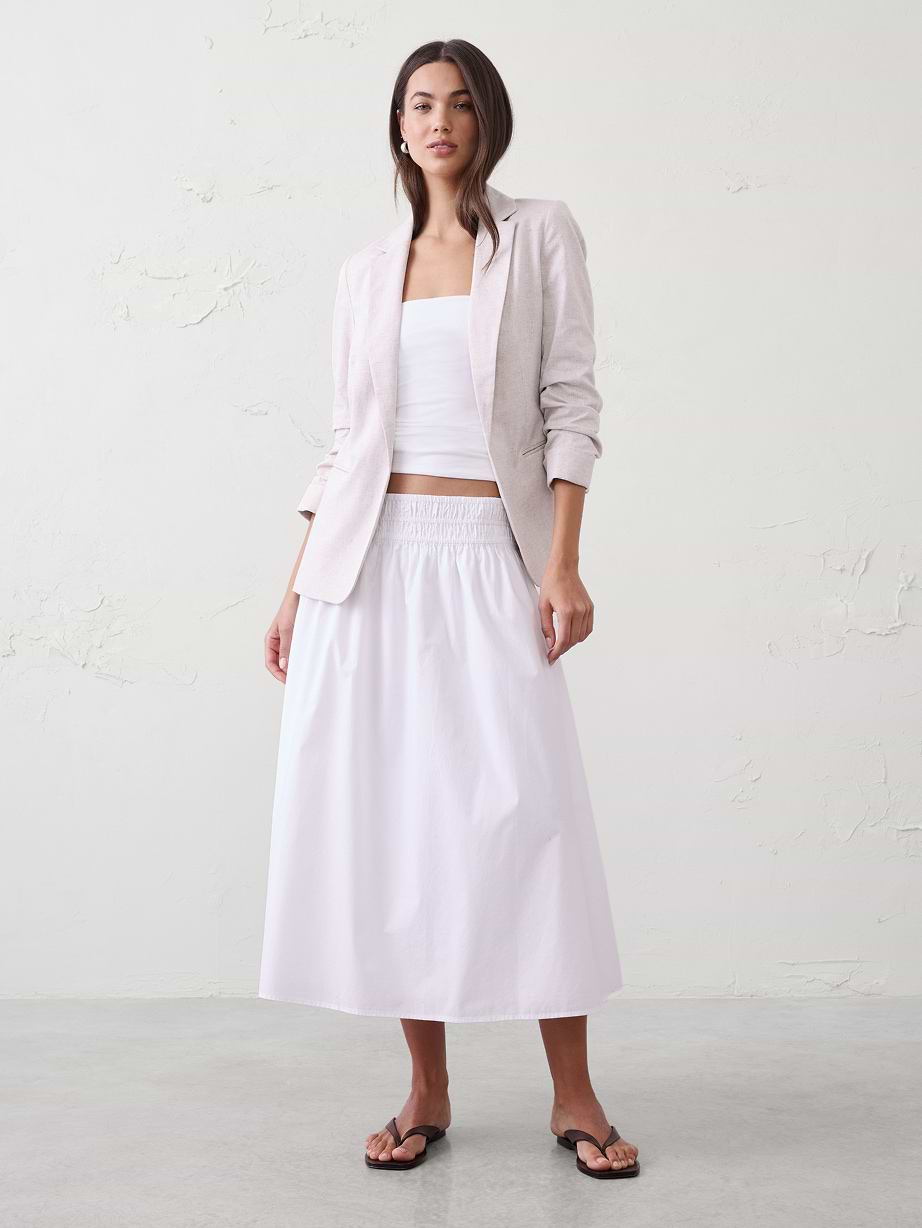 Woman in white shirt and skirt, with blazer.