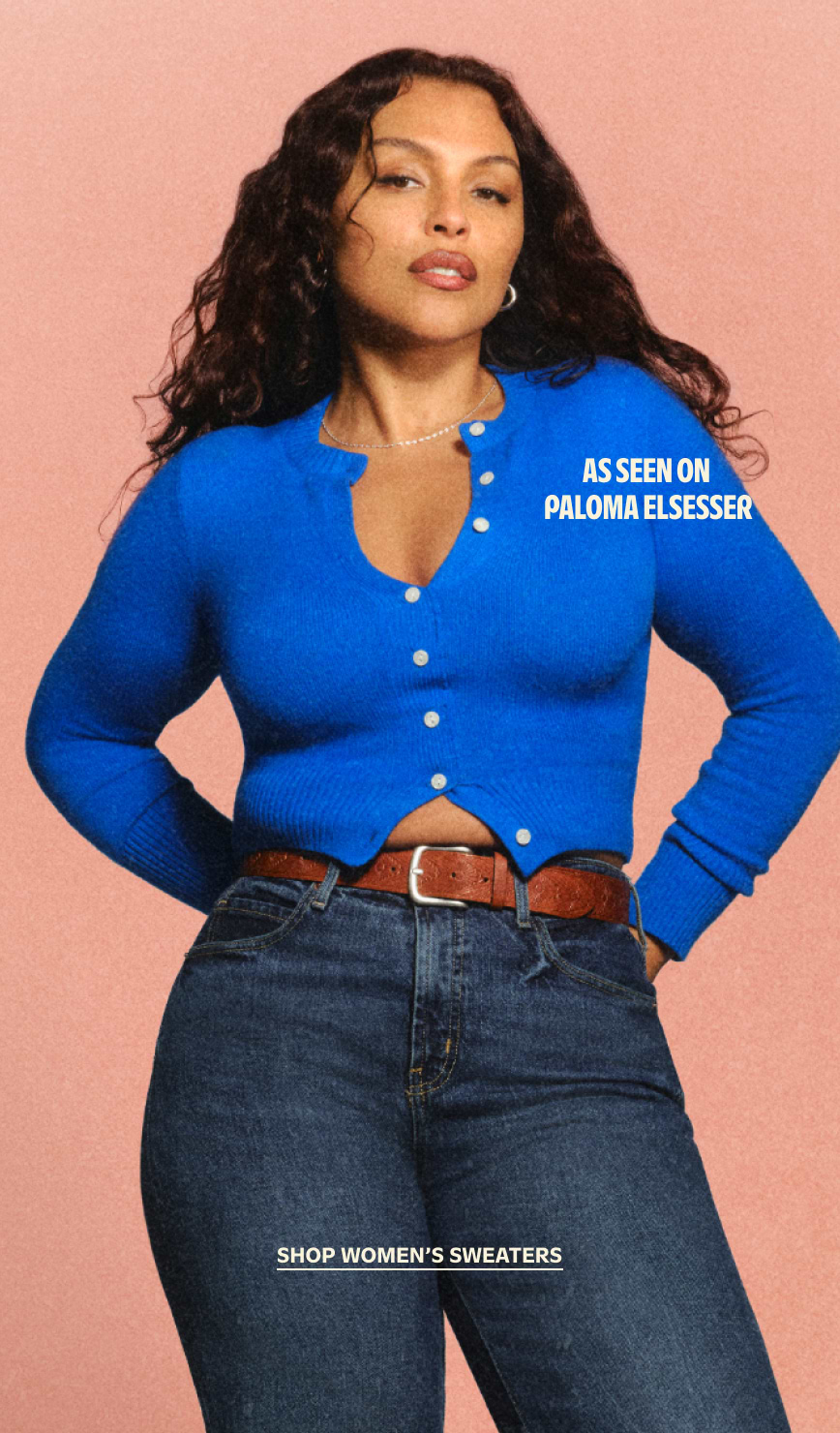 Person in a bright blue buttoned cardigan and dark jeans against a pink backdrop; overlay text: “Shop Women’s Sweaters.”
