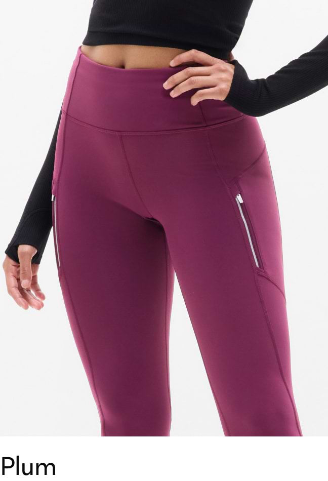 Close-up of plum high-waisted leggings with side zipper pockets, worn with a black long-sleeve crop top.