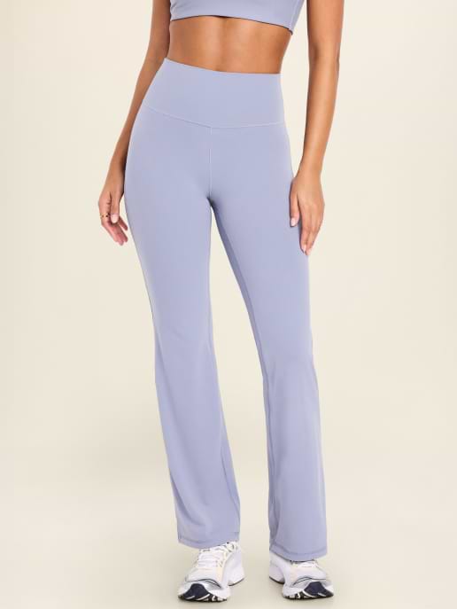 Light purple high-waisted flared yoga pants on a model, paired with white sneakers.
