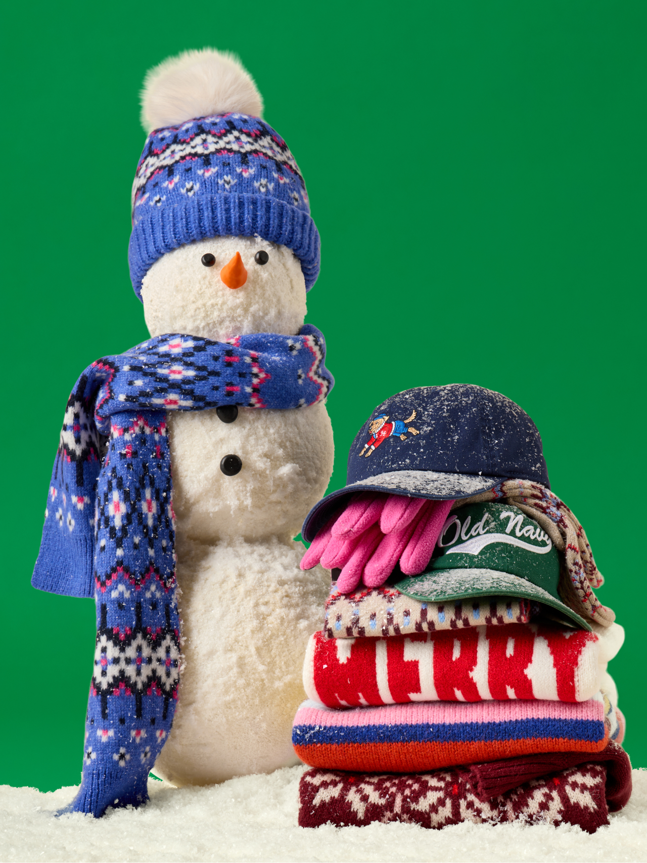 a snowman with a hat, gloves and scarf next to a pile of clothes