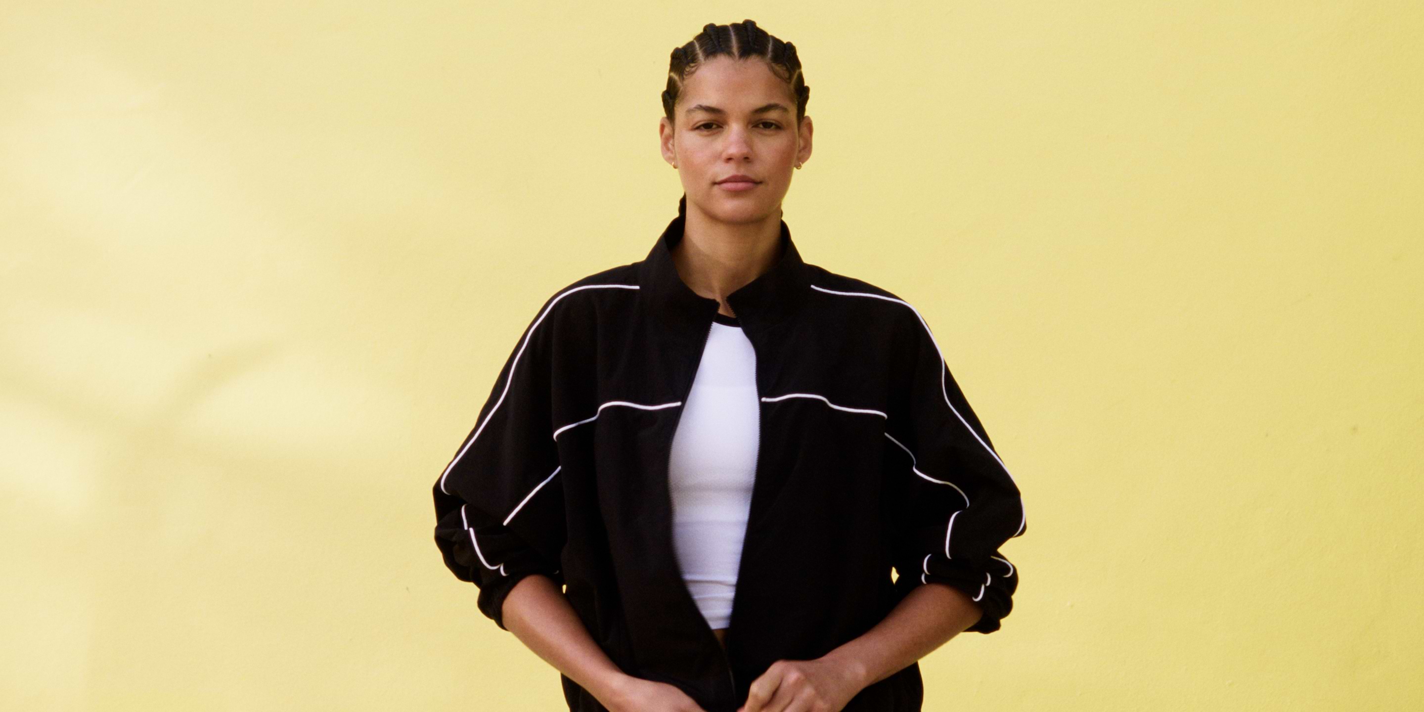 a woman in a black jacket holding a tennis racket