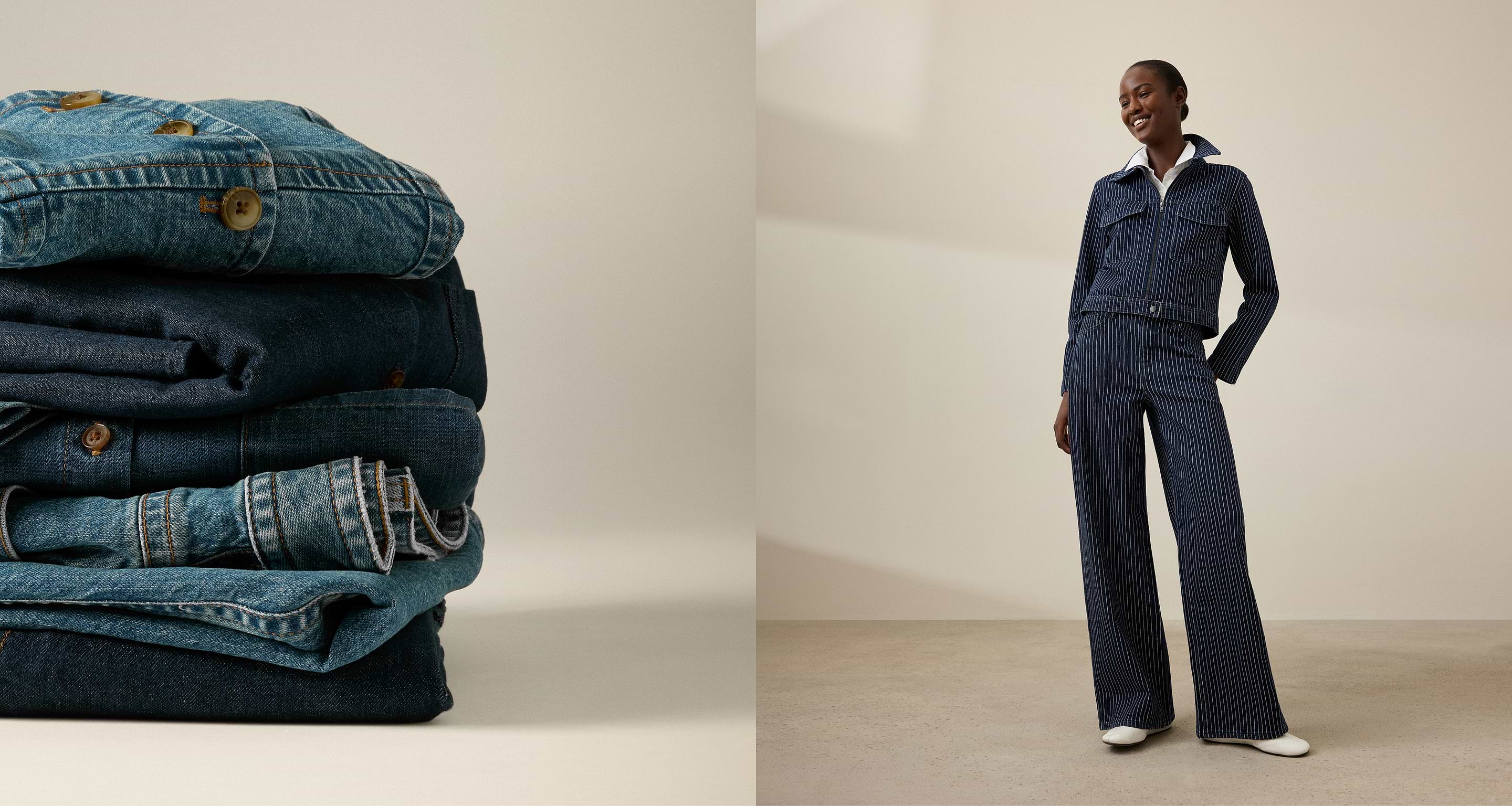 Stacked denim clothes beside a smiling person in a dark blue pinstriped denim jacket and wide‑leg pants against a neutral wall.