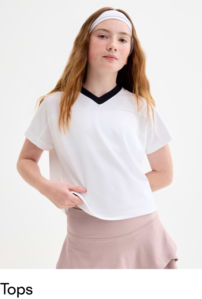 Girl modeling a white perforated V‑neck athletic top with black trim, paired with a mauve tennis skirt.