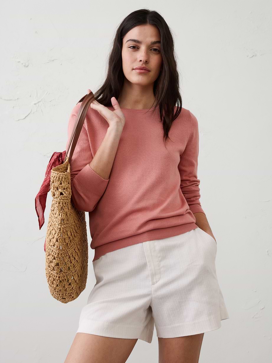 Woman pink sweater, white shorts, and straw purse.