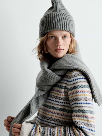 a woman wearing a hat and scarf is posing