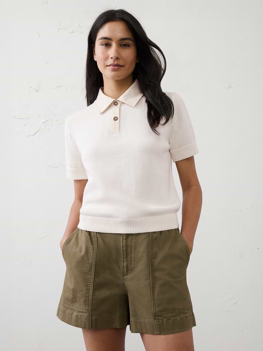 Woman in white polo shirt and green shorts.