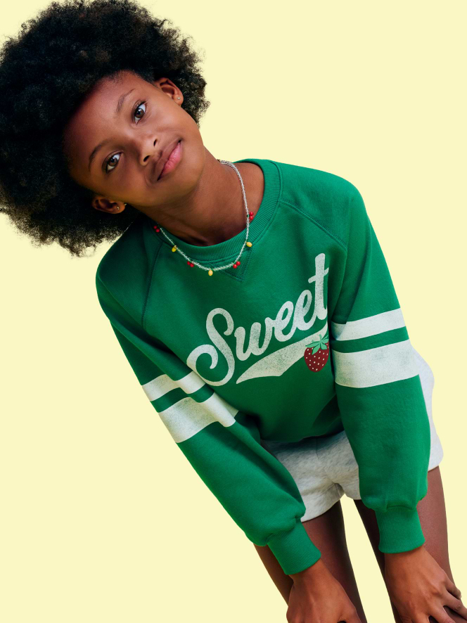 Image of a young girl model wearing an Old Navy graphic crewneck sweatshirt and shorts.