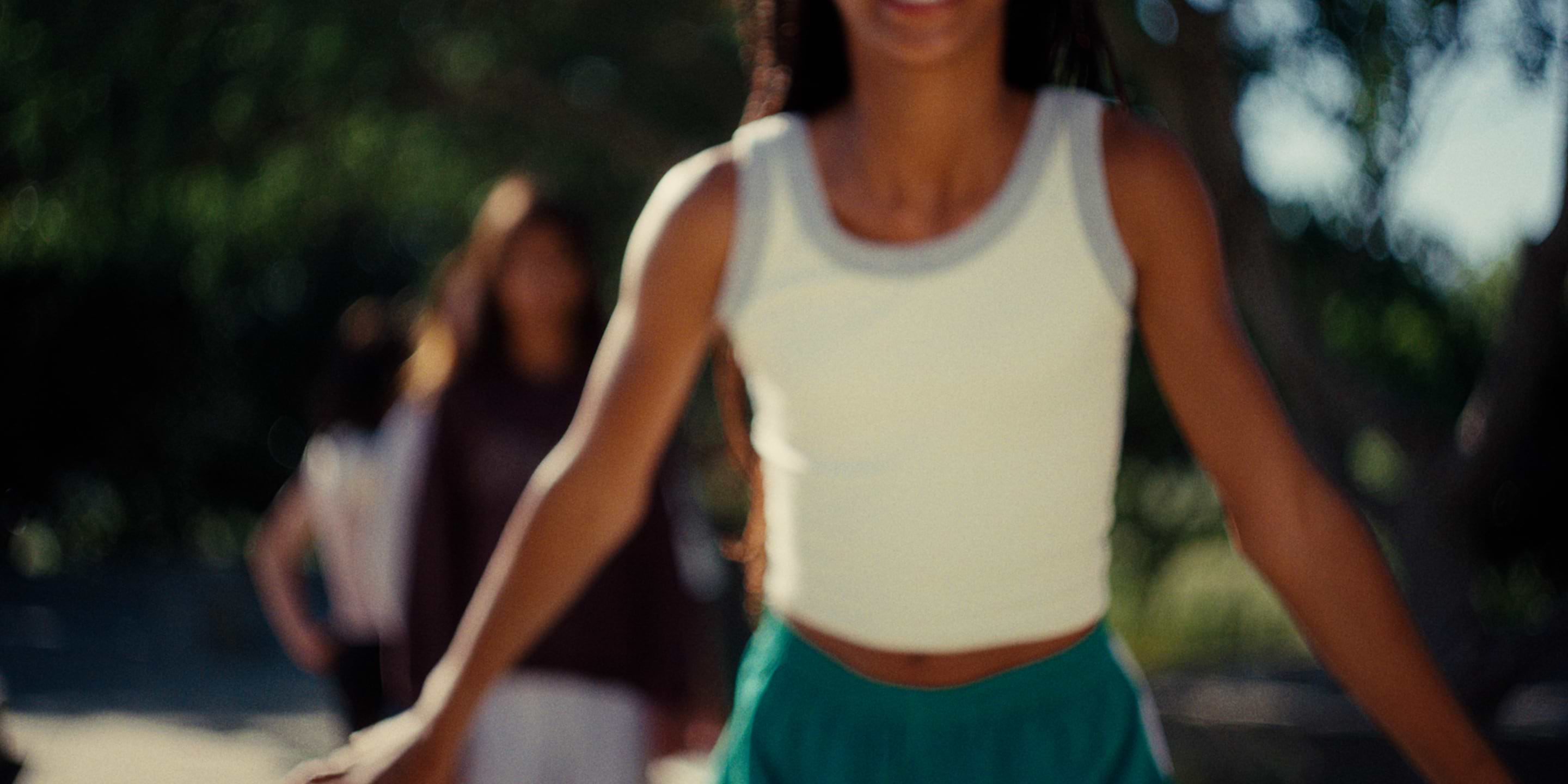 a woman in a white shirt and green skirt riding a skateboard