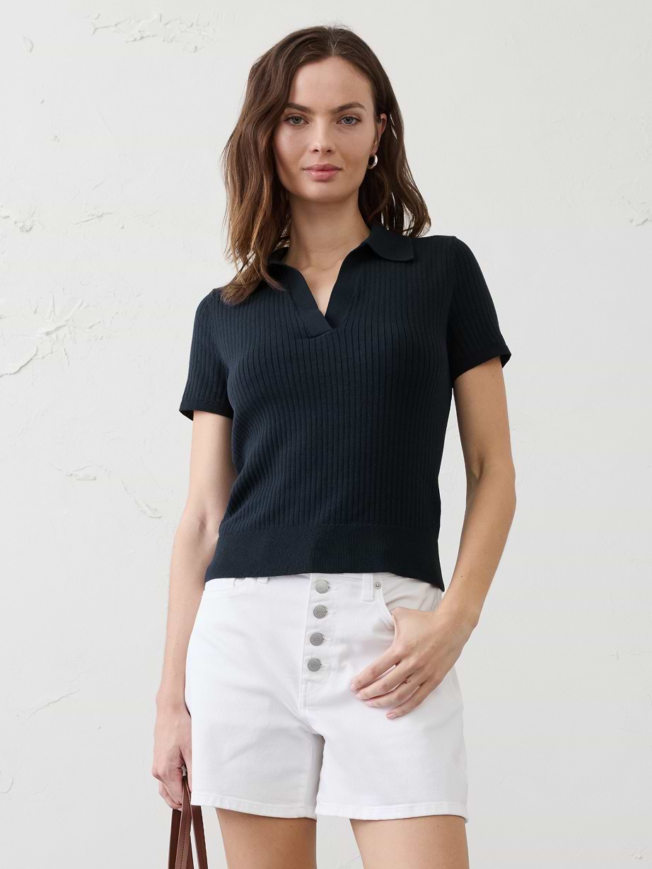 Woman in blue sweater shirt and white shorts.