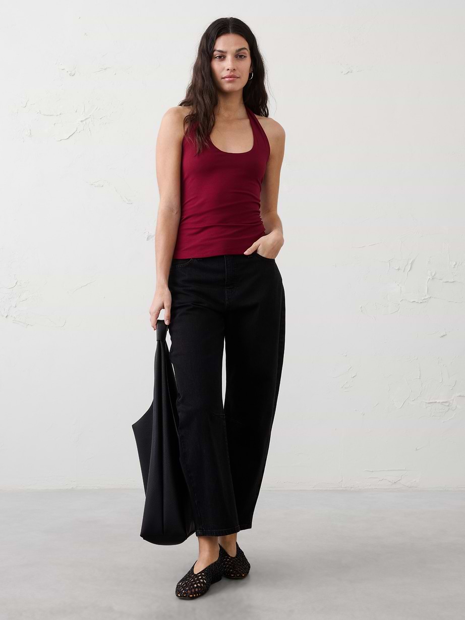 Woman in red tank top, black pants, and black bag.