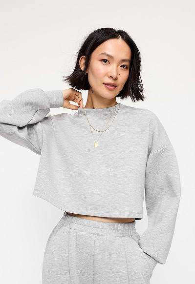 A female model wearing a grey Old Navy cropped sweatshirt.