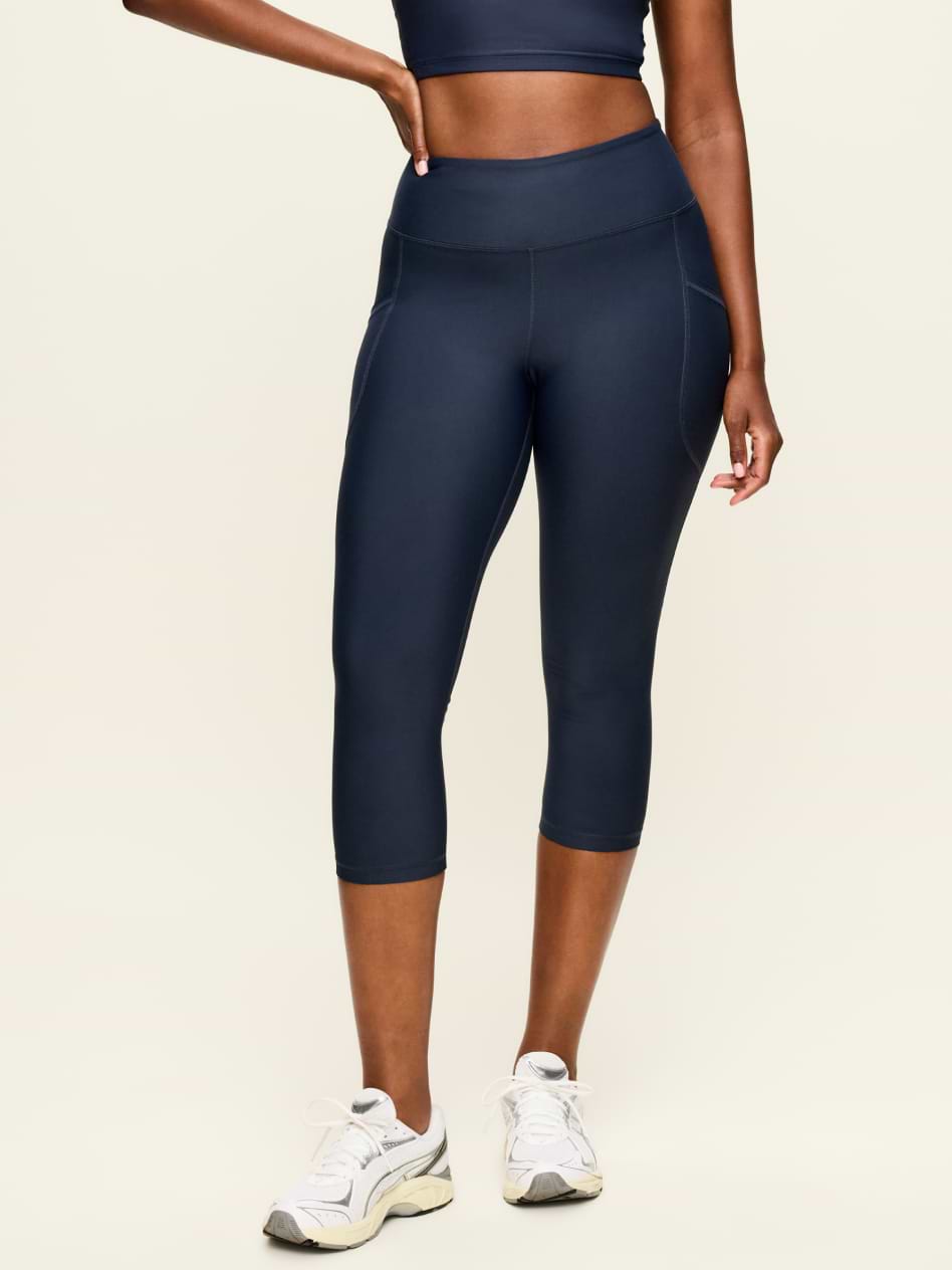 Person modeling navy high-waisted capri leggings with white sneakers, photo cropped at torso; magenta “FPO” text overlay.