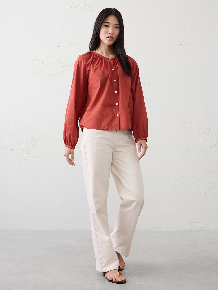 Woman in red blouse and tan jeans.