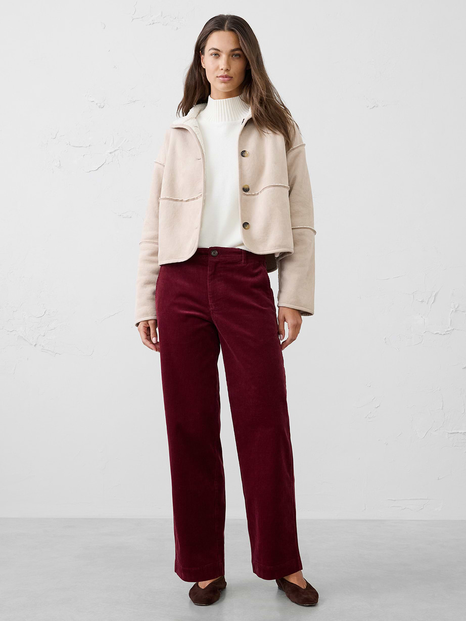 Person wearing a navy denim jacket and matching A-line midi skirt with a tan turtleneck and brown flats, standing indoors.