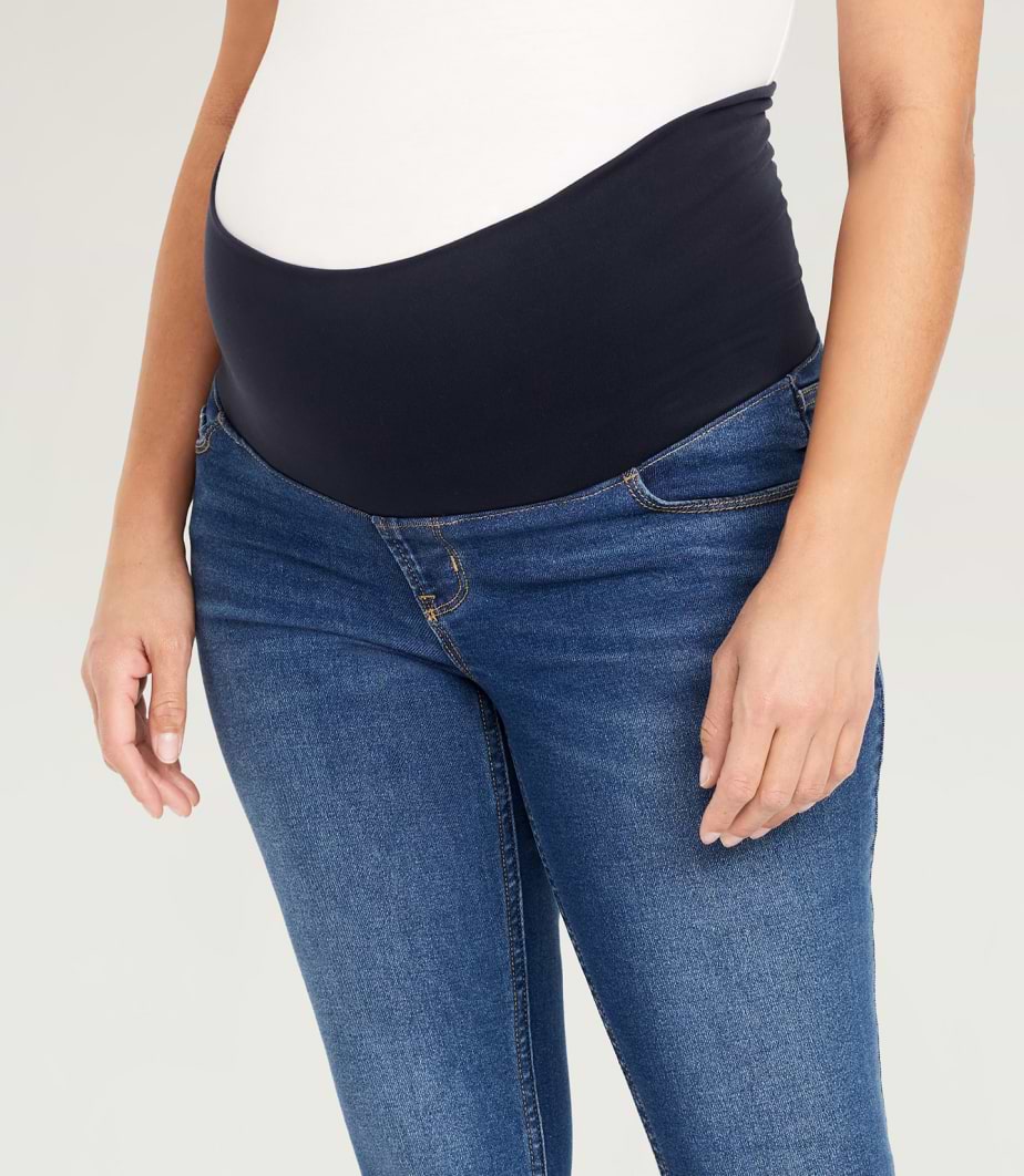 A pregnant model mid bump maternity jeans.