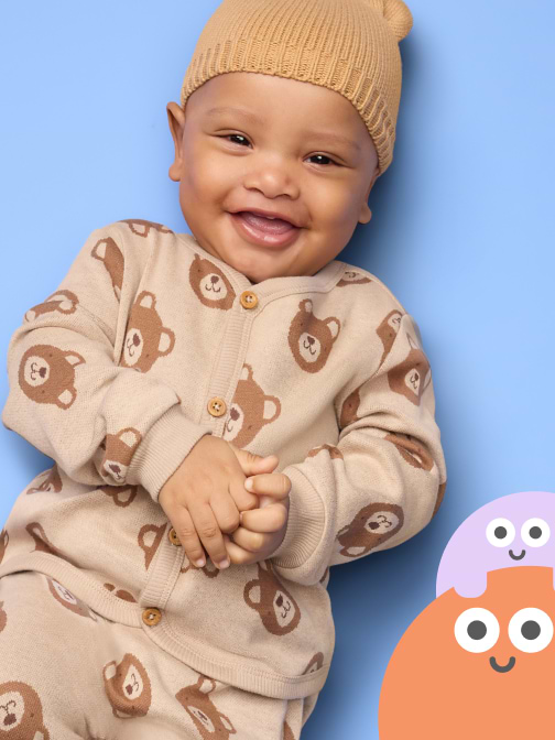 Smiling baby in a beige knit hat and bear-print outfit on a blue background, with two cartoon face circles at the bottom right.